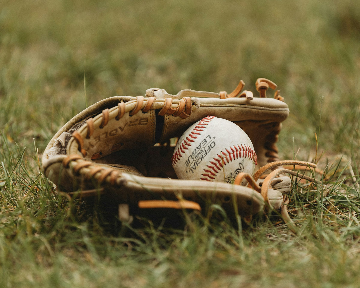 A baseball resting in a glove on the grass